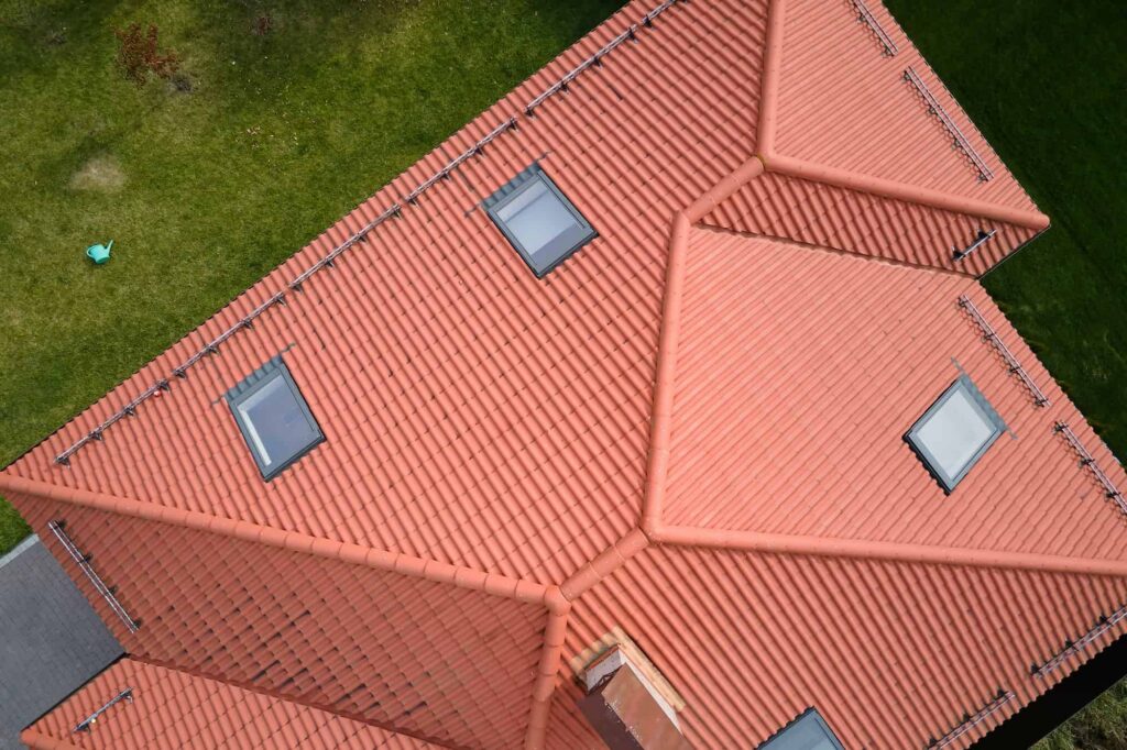 closeup of attic windows on house roof top covered with ceramic shingles tiled covering of building